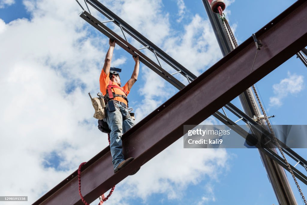 Ironworker at construction site installing roof joist