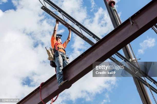 ironworker at construction site installing roof joist - estrutura construída imagens e fotografias de stock