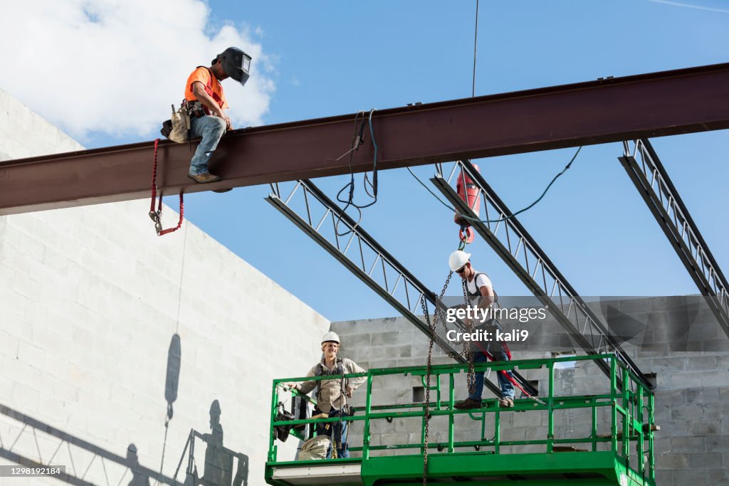 Crew installing roof joists at construction site