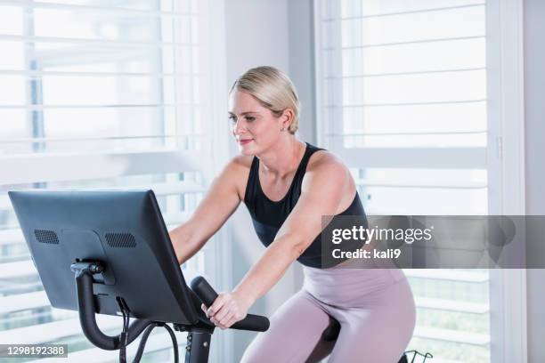 mujer haciendo ejercicio en bicicleta en casa - exercise bike fotografías e imágenes de stock