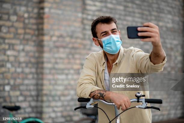 tomar selfie. máscara protectora de la cara, apoyada en la bicicleta. - postureo fotografías e imágenes de stock
