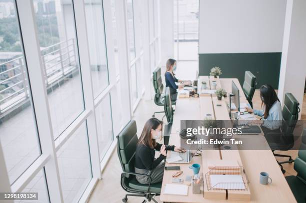 asian chinese beautiful women with protective facemask working in open plan office observing with new sop and social distancing illness prevention safety precautions - social distancing in office stock pictures, royalty-free photos & images