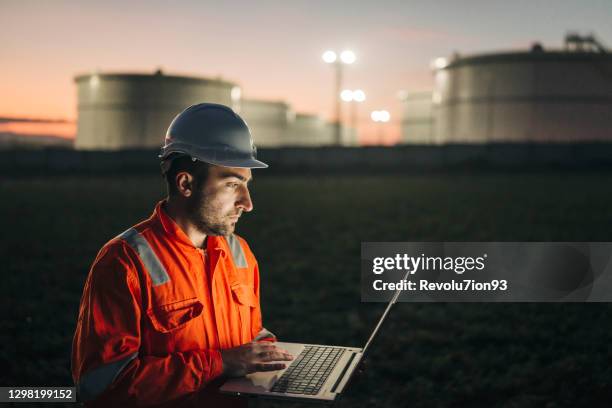 engineer using laptop near oil refinery at night - construction lighting equipment stock pictures, royalty-free photos & images