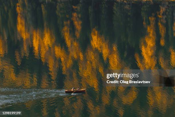 aerial view of boat sailing by beautiful autumn lake with forest reflection in water - alto adige italy stock pictures, royalty-free photos & images