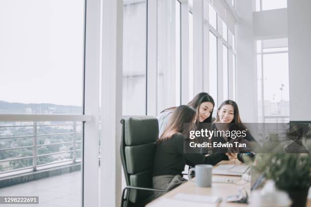 3 asian chinese white collar women having discussion in open plan office looking at smart phone  smiling - business phone meeting stock pictures, royalty-free photos & images