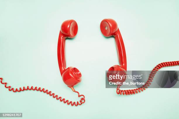 high angle view of two red old-fashioned telephone receiver on turquoise background - public phone stock pictures, royalty-free photos & images