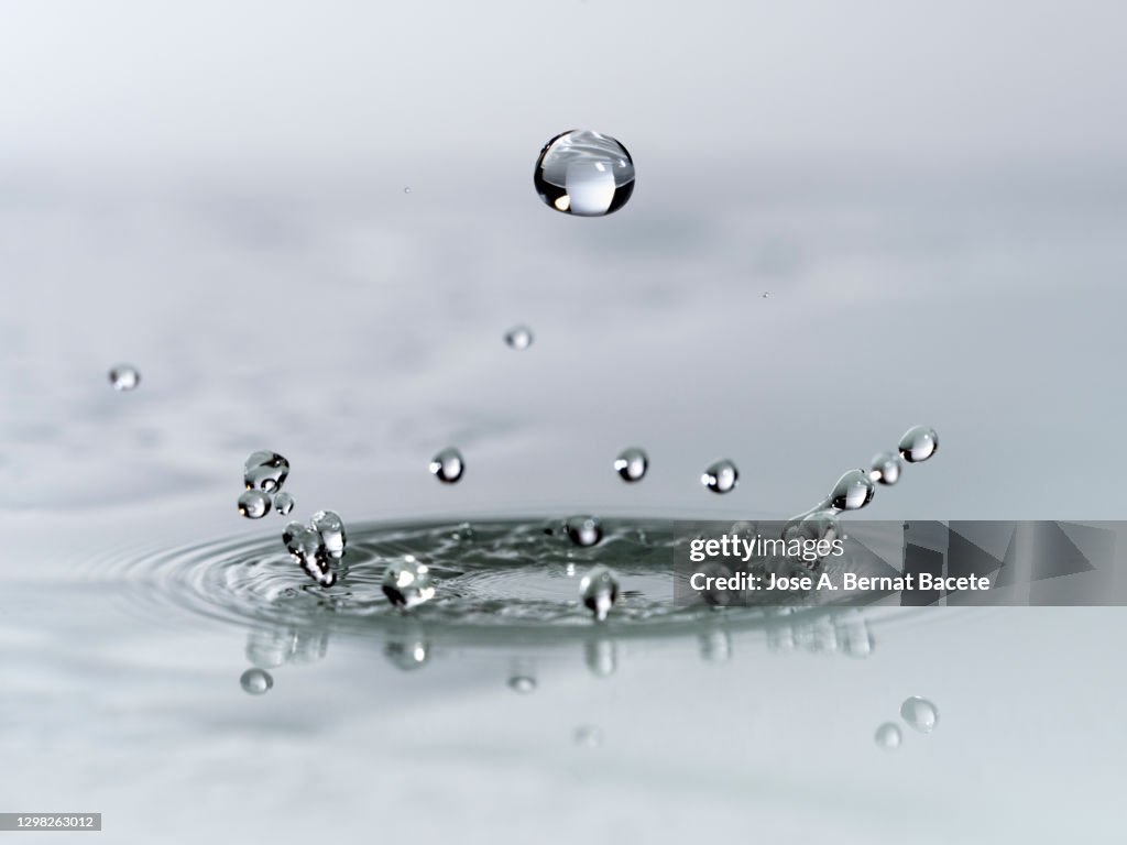 Impact of a drop of water on a liquid surface with a white background.