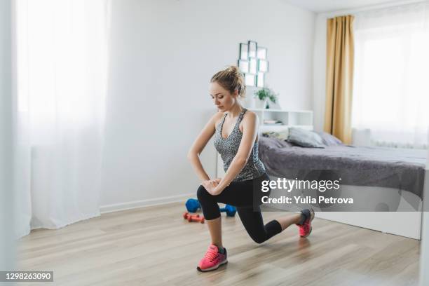 young beautiful woman sports at home in sportswear with dumbbells stretching - home workout stock pictures, royalty-free photos & images