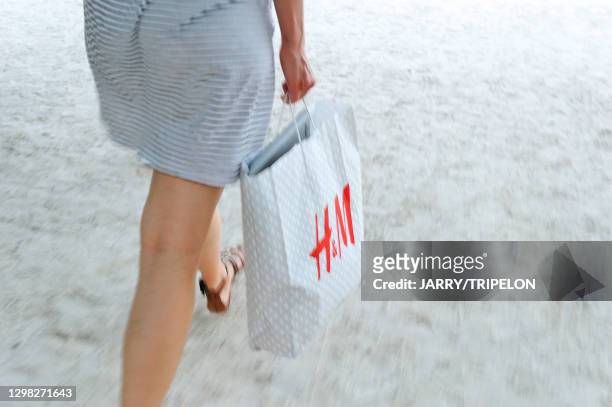 Jeune femme avec une robe courte et portant un sac de la marque H&M, 10 juillet 2015, Paris 1er arrondissement, France.