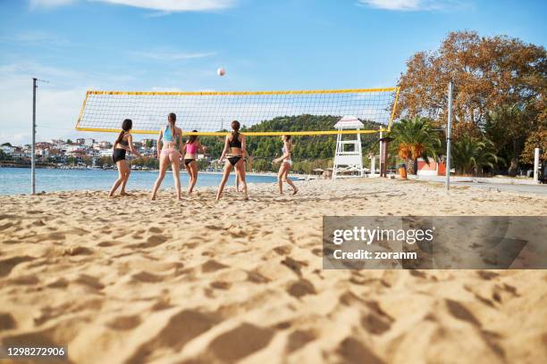 gruppo di giovani donne in bikini che giocano a beach volley per divertimento - beach volley foto e immagini stock