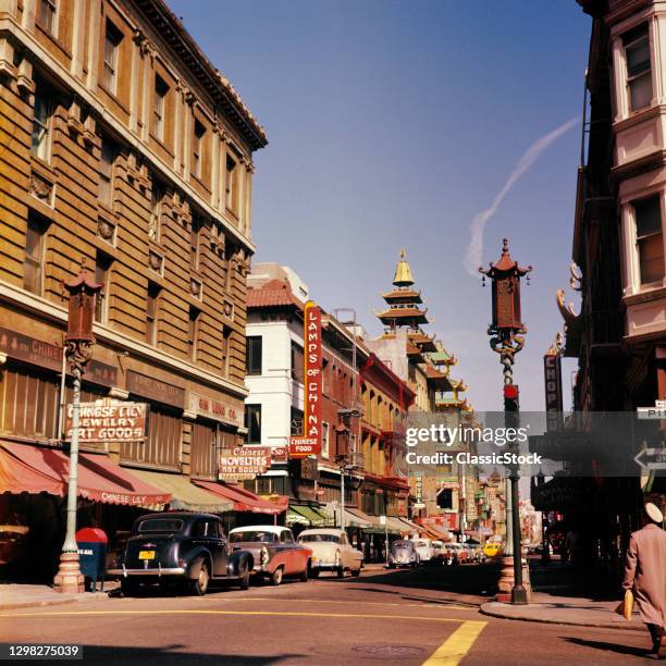 1950s Chinatown Scene Ornate Chinese Styled Street Lamps Shop Signs Parked Cars On Grant Avenue San Francisco California USA.