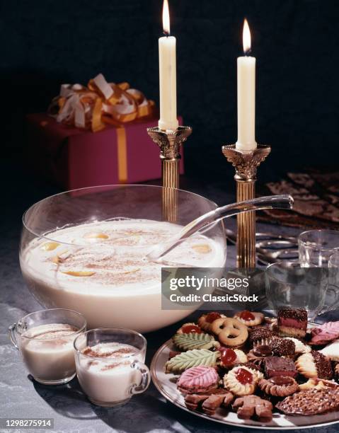 1980s Cups Ladle And Bowl Of Christmas Eggnog Beverage With Plate Of Sugar Cookies Lit Candles And A Wrapped Present.