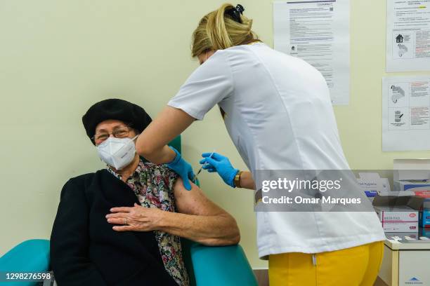 Health worker wears a protective face mask and gloves as she gives a Pfizer/BioNTech COVID-19 jab to an elderly woman at the Krakow University...