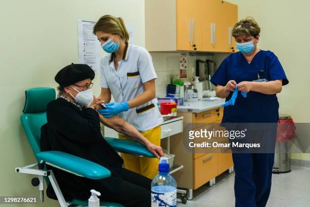 Health worker wears a protective face mask and gloves as she gives a Pfizer/BioNTech COVID-19 jab to an elderly woman at the Krakow University...