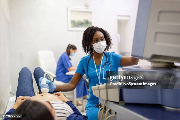 médico femenino haciendo examen por ultrasonido de una mujer embarazada - ecografía fotografías e imágenes de stock