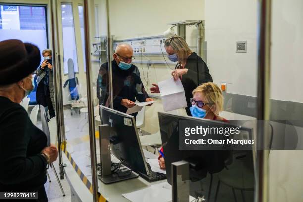 An elderly man wears a protective face mask and speaks to health workers in the observation room after being given a Pfizer/BioNTech COVID-19 jab at...