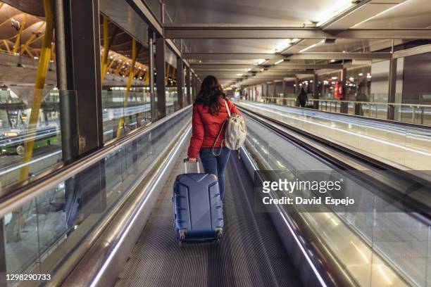 young woman walking in the moving walkway of the airport - travolator stock-fotos und bilder