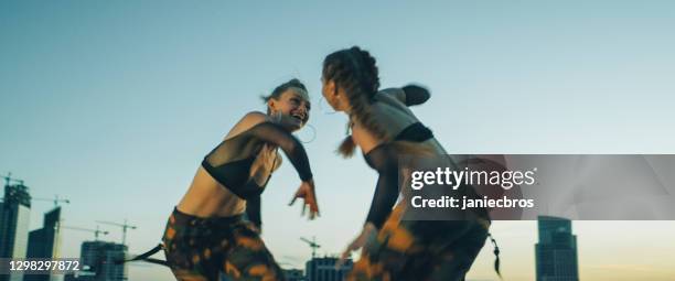 tänzerinnen in camo-outfits treten gemeinsam auf dem sonnigen dach auf. moderne choreographie - rap stock-fotos und bilder