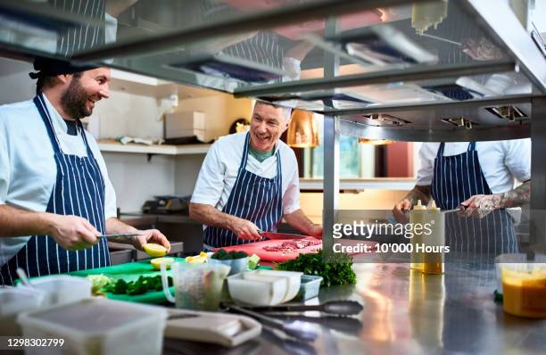 cheerful chefs preparing food in commercial kitchen - chef team stock pictures, royalty-free photos & images