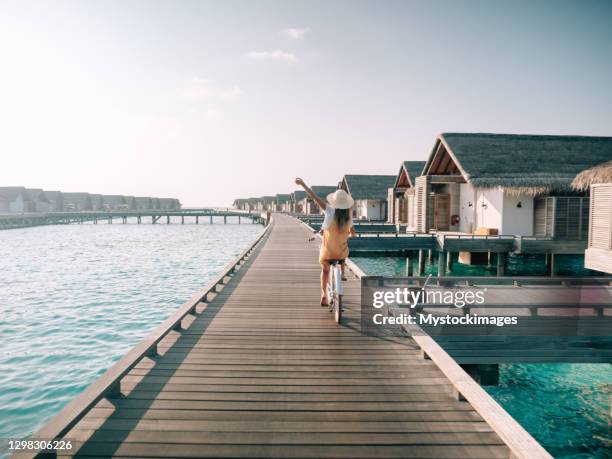 giovane donna in bicicletta su molo di legno alle maldive - luxury hotel foto e immagini stock