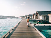 Young woman riding bicycle on wooden pier in the Maldives