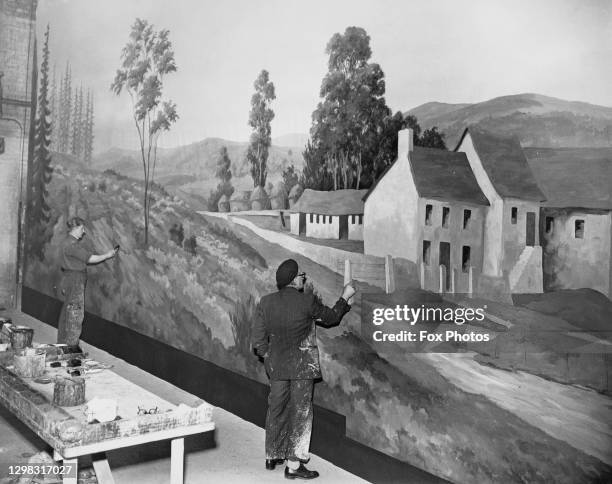 Art student L Warwick and British artist Jack Leonard at work on a section of a mural for the Ideal Home Exhibition, at a studio in Walworth, south...