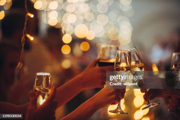 tostadas de celebración feliz con luces de cuerda champán y vino tinto - brindar fotografías e imágenes de stock