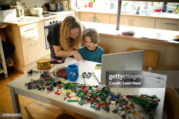 James Laurie, aged 8, is assisted in his online work by his mother Laurette as he continues home schooling, on January 25, 2021 in London, United...