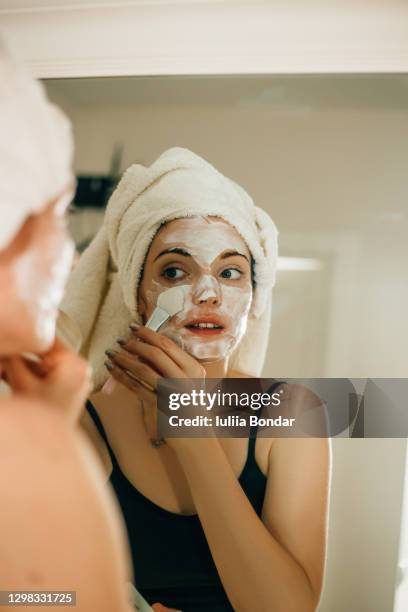 side view shot of young woman applying facial cosmetic mask in bathroom. - mud mask photos et images de collection