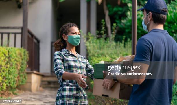men with protective face mask delivering groceries in front of the home, during pandemic lockdown isolation - care package stock pictures, royalty-free photos & images