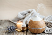 Cozy composition with an air humidifier, a set of aromatic oils and a candle.