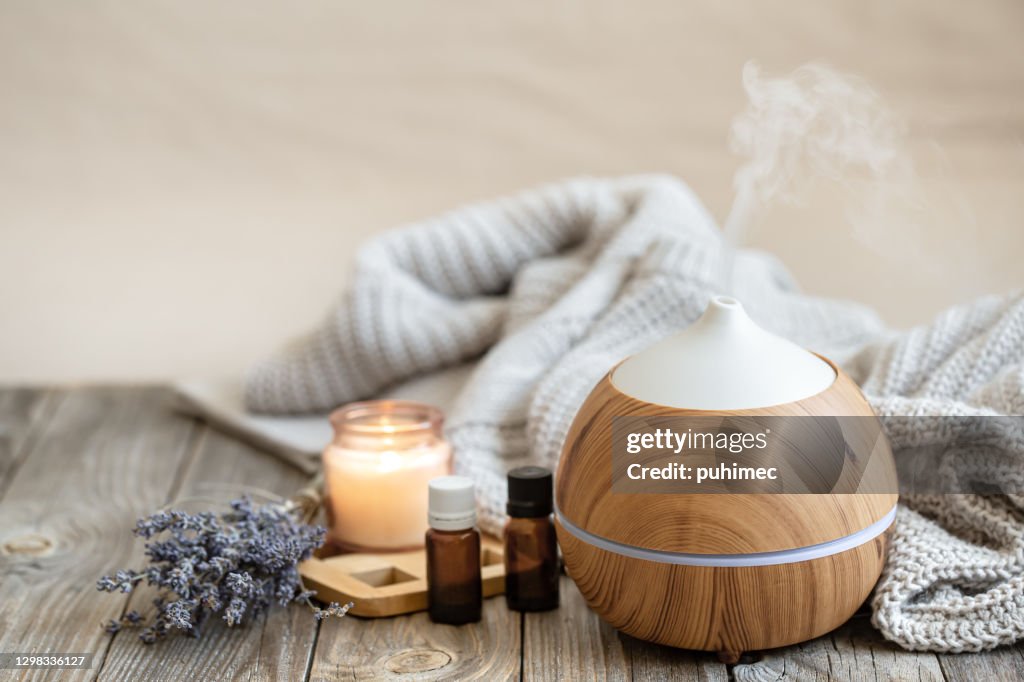 Cozy composition with an air humidifier, a set of aromatic oils and a candle.