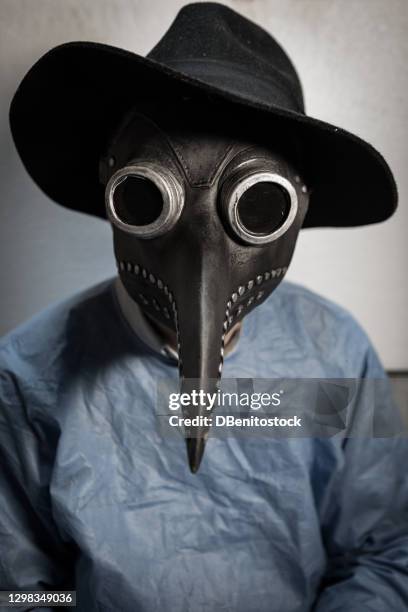 portrait of a doctor wearing a ppe and a retro mask that was worn during the bubonic plague - men costume black and white stock-fotos und bilder