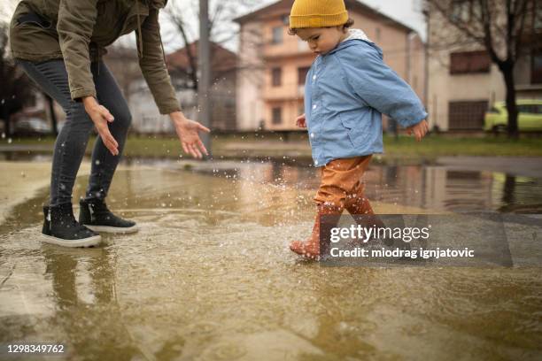 moeder die pret met haar zoon in plas op de herfstdag heeft - family shoes stockfoto's en -beelden