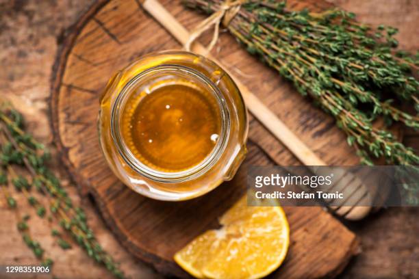 pot de miel avec le groupe de feuilles de thym sur la table rustique - miel photos et images de collection