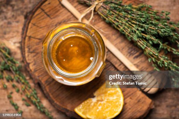 jar of honey with thyme leaves bunch on rustic table - honey jar stock pictures, royalty-free photos & images