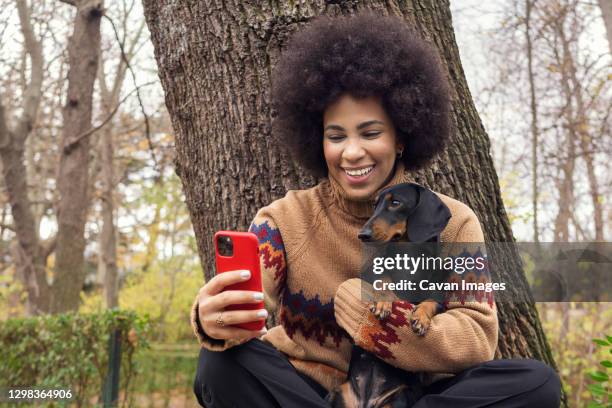 a cuban girl taking a selfie with her dachshund in the park - a fall from grace 個照片及圖片檔