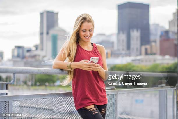 female millennial using smartphone with city behind - montreal people stock pictures, royalty-free photos & images