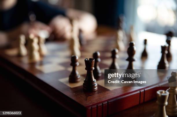 close up of pieces in a chess game with child blurred in background. - rook chess piece stock pictures, royalty-free photos & images