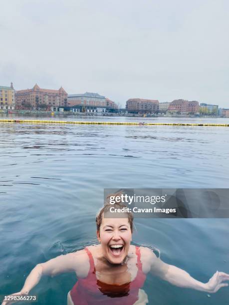 smiling woman full of joy cold water swimming in denmark - floating on water stock-fotos und bilder