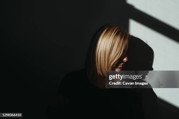 woman's profile in bright light with black background and shadows - portrait professional dark background stock pictures, royalty-free photos & images