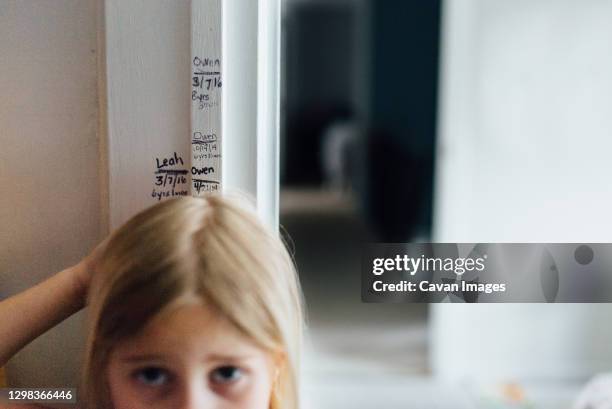 measuring girl's height at home on door frame - measure stock-fotos und bilder