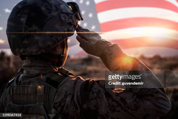 female solider saluting us flag at sunrise - armed forces stock-fotos und bilder