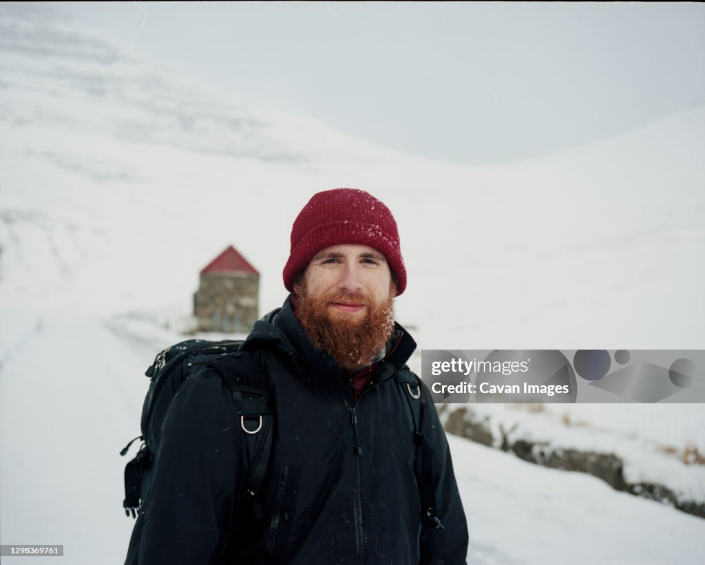 Portrait of smiling bearded man, in the snow, looking at camera, in the Faroe Islands