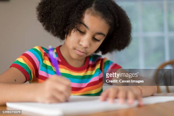 ten year-old bi-racial girl doing homework at table - 10 11 jaar stockfoto's en -beelden