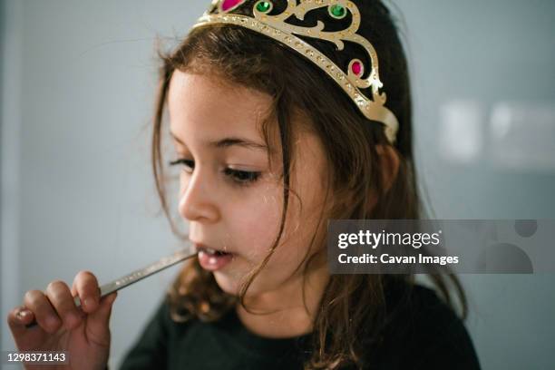 4 year old girl wearing tiara and eating from measuring spoon - little princess stock pictures, royalty-free photos & images