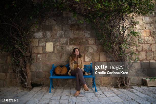 woman reading a book in old city - israeli stock-fotos und bilder