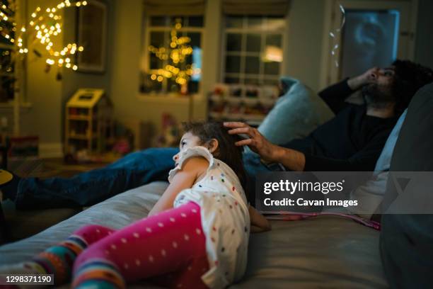 father and daughter relaxing on couch and watching a movie - kunst cultuur en vermaak stockfoto's en -beelden