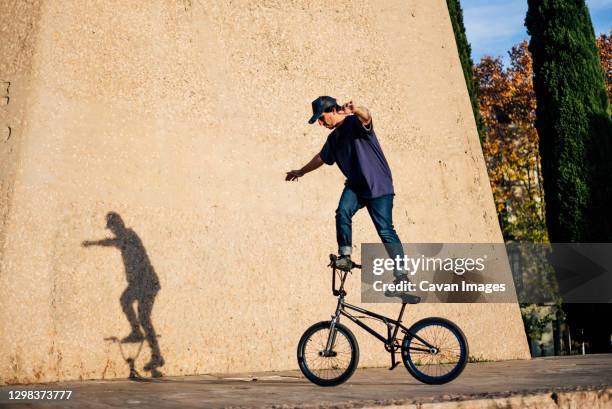 man practicing tricks with the bmx bike in the city - bicycle stunt stock pictures, royalty-free photos & images