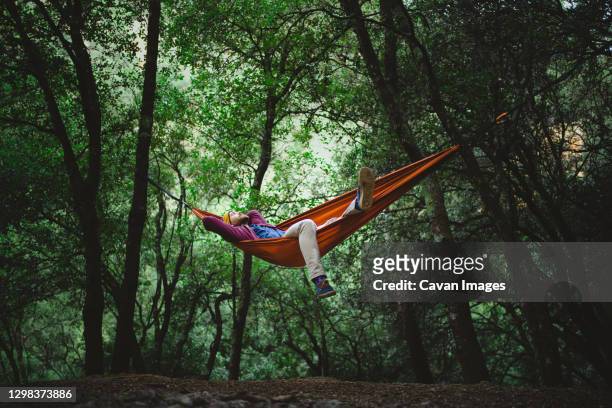 young male rests on a hammock in the middle of the forest - hammock foto e immagini stock